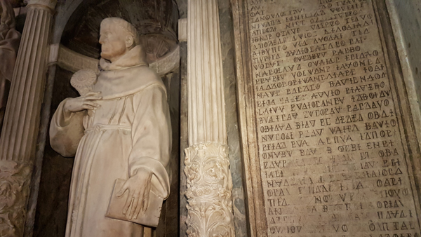 Statua di san Bernardino, con a lato la misteriosa epigrafe