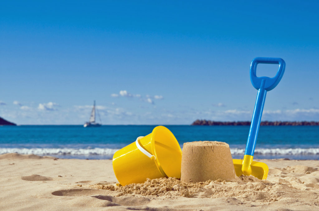 Shot of the beach with a spade and bucket in foreground.